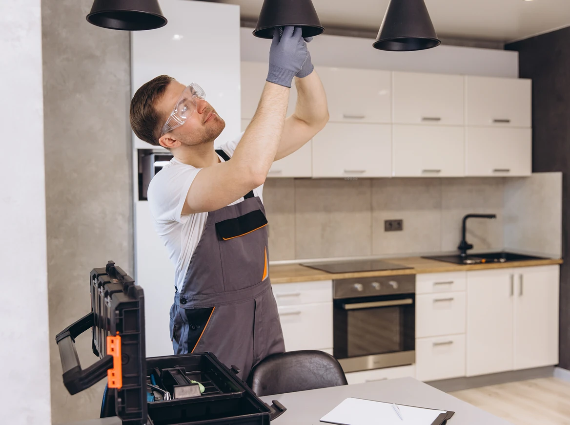 A man installing a light fixture in a modern kitchen.